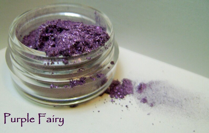 May include: A small glass jar filled with purple glitter eyeshadow. The jar is labeled "Purple Fairy".