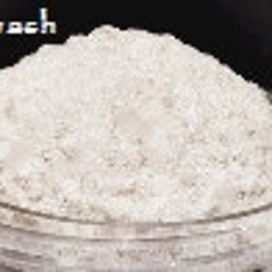 May include: A close-up of a white powder, called "Whitewash", in a glass container.