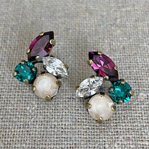 May include: A pair of cluster earrings featuring a combination of colorful gemstones. The earrings showcase a mix of round, marquise, and pear-shaped crystals in shades of pink, teal, white, and cream, set in a gold-tone metal.