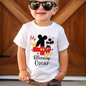 May include: White t-shirt with a red number four and Mickey Mouse wearing sunglasses. The text on the shirt reads "My 4th Birthday Oscar".
