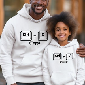 May include: White hooded sweatshirts with a black graphic of computer keys. The text on the sweatshirts reads "Ctrl + C (Copy)" and "Ctrl + V (Paste)".