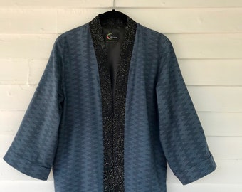 Op de afbeelding: Een blauwe en zwarte kimono-jas met een zwarte bies en een label met de tekst "Urban Threads".
