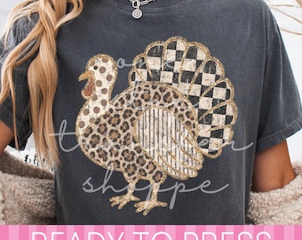 May include: A charcoal gray t-shirt featuring a graphic of a turkey with a multi-patterned design. The turkey body has leopard print, polka dots, vertical stripes, and a black and white checkered tail. The text READY TO PRESS is visible.