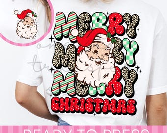 May include: A white t-shirt featuring a large graphic on the back with the text MERRY MERRY MERRY CHRISTMAS in red, green, and leopard print patterns, centered around a vintage-style Santa Claus illustration. A small matching Santa icon is on the front.