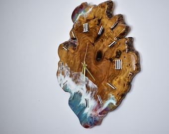 May include: A unique wall clock crafted from a piece of wood, featuring a natural edge and a resin design. The clock face has Roman numerals and gold-colored hands. The resin design incorporates shades of blue, white, and brown.