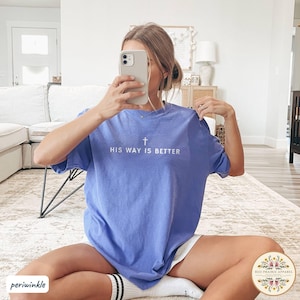 May include: Periwinkle blue t-shirt with the text "HIS WAY IS BETTER" and a cross graphic. The shirt is a solid color and appears to be made of soft material. The shirt is part of the Red Prairie Apparel collection.