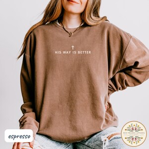 May include: Espresso-colored sweatshirt with the text "HIS WAY IS BETTER" and a cross graphic. The sweatshirt has a crew neck and long sleeves. The bottom left corner of the image has the word "espresso".
