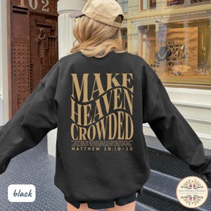 May include: A black long-sleeve sweatshirt featuring gold text on the back that reads "MAKE HEAVEN CROWDED" in a large, wavy font, followed by smaller text "MATTHEW 28:19-20" and a longer passage of scripture printed in a smaller, standard font.