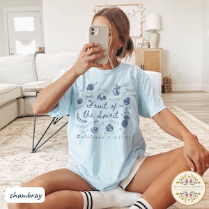 May include: Light blue t-shirt with the text "Fruit of the Spirit" and illustrations of various fruits. The text "Galatians 5:22-23" is also printed on the shirt. The shirt is labeled "chambray" and has a Red Prairie Apparel logo.