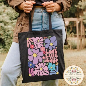 May include: Black canvas tote bag with a floral design and the text "Love Like Jesus" in colorful letters.