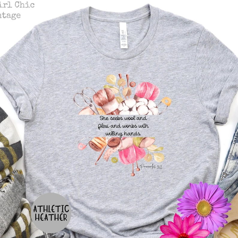 Proverbs 31:13 t shirt with images of pink, white and green knitting needles, crochet hooks, yarn and foliage.