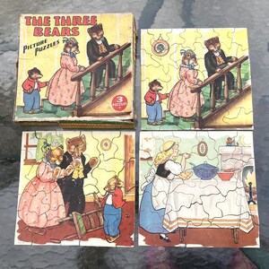 May include: A vintage The Three Bears Picture Puzzles set including a cardboard box and three completed jigsaw puzzles. The illustrations depict anthropomorphic bears in clothing and a young girl in a kitchen, all rendered in a classic storybook style.