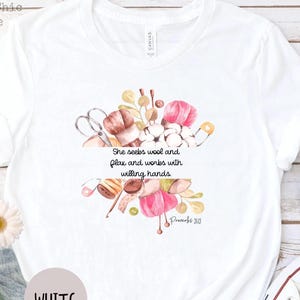 Proverbs 31:13 t shirt with images of pink, white and green knitting needles, crochet hooks, yarn and foliage.