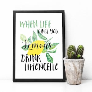 Puede incluir: Una impresión enmarcada en negro con el texto "When life gives you lemons, drink limoncello" en letras blancas. La impresión presenta una ilustración de acuarela de limones en una rama con hojas verdes.