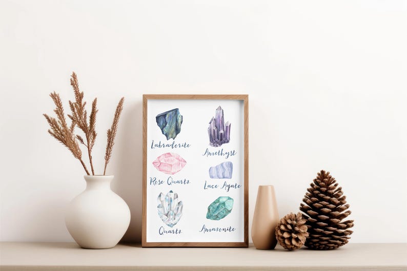 May include: A framed print featuring watercolor illustrations of various crystals, including Labradorite, Amethyst, Rose Quartz, and Quartz. The print is displayed on a neutral-toned surface, accompanied by decorative elements like a vase and pinecones.