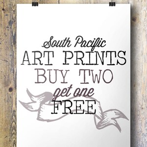 K&ouml;nnte beinhalten: Wei&szlig;es Schild mit schwarzem Text, der "South Pacific Art Prints Buy Two Get One Free" lautet. Unter dem Text befindet sich ein dekoratives Banner mit einem grau-wei&szlig;en Design.