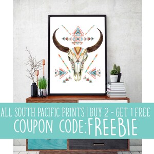 May include: Framed art print featuring a watercolor illustration of a bull skull with geometric patterns in teal, orange, and red. The artwork is displayed on a wooden cabinet. Text on the image reads: ALL SOUTH PACIFIC PRINTS | BUY 2 - GET 1 FREE COUPON CODE: FREEBIE.