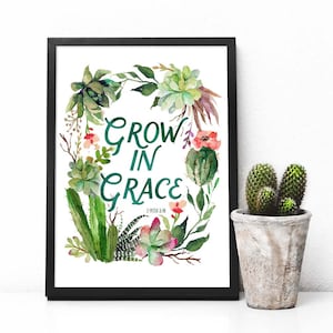 K&ouml;nnte beinhalten: Ein gerahmter Druck mit einer Aquarell-Illustration von Sukkulenten und Kakteen in einer Kranzform. Der Text "Grow in Grace" ist in gr&uuml;ner Schrift mit dem Schriftzitat "2 Petrus 3:18" darunter geschrieben.