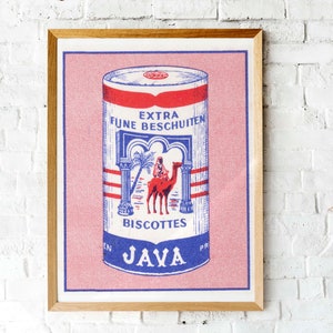 May include: Framed vintage print featuring a cylindrical tin of "Extra Fijne Beschuiten" biscuits. The design includes a red, white, and blue color scheme with an illustration of a person riding a camel. The word "JAVA" is at the bottom.