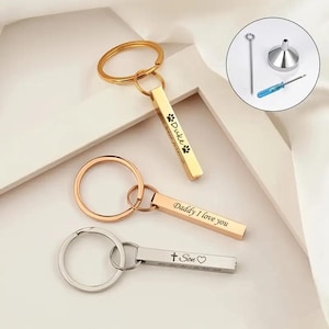 Puede incluir: Tres llaveros de oro y plata con barras grabadas. Las barras están grabadas con las palabras "Duke", "Daddy I love you" y "Son".