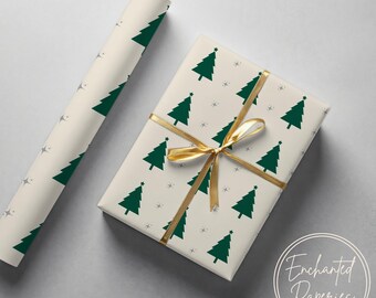 May include: A rectangular gift box wrapped in cream-colored paper featuring a repeating pattern of dark green Christmas trees and small gray stars, tied with a gold ribbon. A matching roll of wrapping paper is positioned to the left of the box.