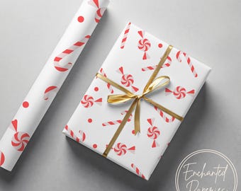 May include: A roll of wrapping paper and a rectangular gift box wrapped in the same white paper featuring a repeating pattern of red and white candy canes, round peppermint candies, and small red dots, tied with a metallic gold ribbon.