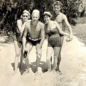 Vintage strandfoto 1960 - twee jonge vrouwen curvy dameszwempakken, gespierde heren zwembroek - retro momentopname
