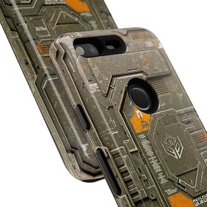 May include: A weathered, industrial-style phone case with a detailed, textured design in shades of gray, brown, and orange. The case features a camera cutout and a fingerprint sensor, with a geometric pattern and a logo.