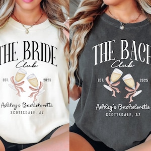 May include: Two white and black t-shirts with a bachelorette party theme. The text on the shirts reads "The Bride Club" and "The Bach Club" with the year 2025 and the text "Ashley's Bachelorette Scottsdale, AZ".