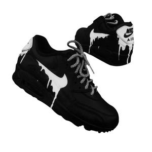 May include: Black and white Nike Air Max 90 sneakers with a unique drip design. The shoes feature white swoosh logos and laces, with a dripping paint effect. The Nike Air logo is visible on the heel.