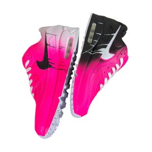 May include: Pair of vibrant pink and black athletic shoes with white soles and laces. The shoes feature a gradient design, transitioning from pink to black, with a black swoosh logo on the side. The shoes are designed for running or casual wear.