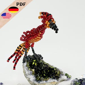 May include: A beaded bird figurine with red, orange, and black beads. The bird is perched on a green and black crystal rock.