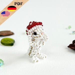 Peut inclure: Un lapin en perles blanches portant un chapeau en perles rouges. Le lapin est assis les pattes repliées sous son corps.