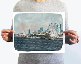 Puede incluir: Una ilustración de acuarela del horizonte de Seattle con la icónica noria en primer plano. La ciudad se representa en tonos apagados de azul, verde y marrón, con un cielo nublado por encima. El agua es de un azul profundo con líneas blancas que representan las olas.
