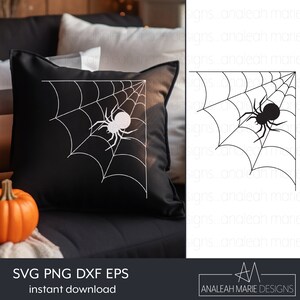 Op de afbeelding: Een zwart kussen met een wit spinnenweb- en spinnenontwerp in de hoek. Het kussen ligt op een zwarte bank met een wit deken en twee oranje pompoenen.