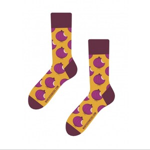 Może przedstawiać: Para żółtych skarpet z wzorem fioletowych cebuli. Skarpety mają bordowy mankiet, a na skarpetach nadrukowany jest tekst "whatgeekneeds.com".