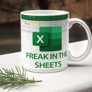 Könnte beinhalten: Weiße Keramiktasse mit einem grün-weißen Design, das das Microsoft Excel-Logo und den Text "Freak in the Sheets" zeigt.