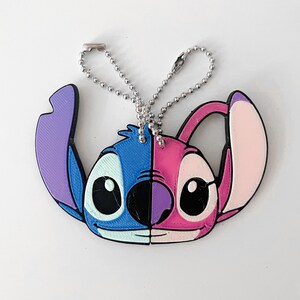 Pode incluir: Um chaveiro Stitch e Angel azul e rosa com uma corrente prateada. O chaveiro apresenta os rostos dos dois personagens, Stitch &agrave; esquerda e Angel &agrave; direita.