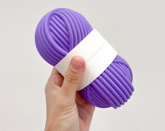 Uma caixa em formato de novelo de lã. Um pequeno estojo para materiais de costura e crochê.