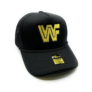 May include: Black trucker hat with a gold embroidered "WF" logo. The hat has a black mesh back and a black brim. The hat has a "Hatzone" tag with the text "Official Licensed Product".