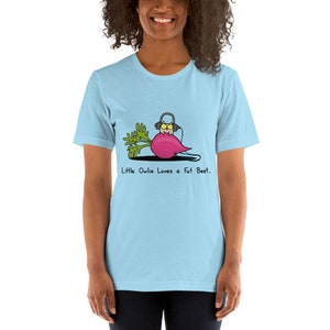 May include: A light blue t-shirt featuring a cartoon illustration of an owl wearing headphones and sitting on a beet. The text "Little Owlie Loves a Fat Beet." is printed below the illustration.
