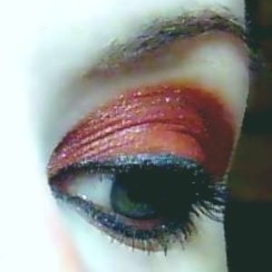 May include: Close-up of a copper-toned eyeshadow look with a black eyeliner and mascara. The eyeshadow has a shimmery finish.