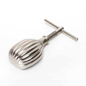 Puede incluir: Un cascanueces plateado con un cuerpo ovalado y acanalado y un mango en forma de T. El mango está conectado al cuerpo por una varilla roscada. Esta herramienta está diseñada para romper nueces.