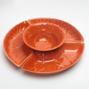 Peut inclure: Un ensemble de quatre plats de service en céramique orange. Les plats sont en forme de pétales de fleurs et s'emboîtent pour former un grand plat de service. Le plat central est un bol rond.