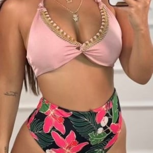 May include: A two-piece swimsuit featuring a halter top and high-waisted bottoms. The top is a solid light pink with gold trim, while the bottoms have a black background with a vibrant floral pattern in pink and green.
