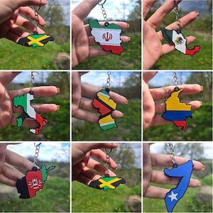 Puede incluir: Una colección de llaveros con diferentes formas de países con sus respectivas banderas. Los llaveros están hechos de goma negra y tienen cadenas plateadas. Las banderas incluyen Canadá, Reino Unido, Sri Lanka, Jamaica, Irán, México, Italia, Guyana, Colombia, Afganistán, Bahamas, Somalia, China y Trinidad y Tobago. Los llaveros están dispuestos en una cuadrícula sobre un fondo blanco. La imagen también incluye un logotipo con el texto "KULTURAL DIVERSITY" y un globo terráqueo con banderas de diferentes países.