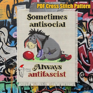 May include: A cross-stitch pattern featuring Eeyore from Winnie the Pooh, with the text "Sometimes antisocial Always antifascist." The design includes a red balloon and is set against a graffiti background. The words "PDF Cross Stitch Pattern" are at the top.