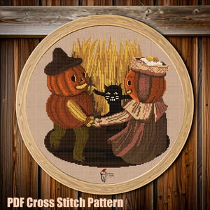 Puede incluir: Patrón de punto de cruz con una pareja de calabazas con un gato negro entre ellos. Las calabazas llevan sombreros y el gato mira al espectador. El fondo es un campo de trigo.