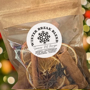 May include: A clear cellophane bag filled with dried orange slices, cinnamon sticks, star anise, and cloves. A round label reads "Winter Break Blend" with a snowflake design and "Simmer Pot Recipe" below. The ingredients are listed.