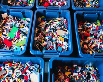 May include: Eight blue plastic bins filled with colorful Lego bricks. The bins are arranged in three rows, with three bins in the top row, three bins in the middle row, and two bins in the bottom row.
